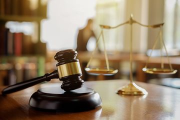 a gavel sits on a table next to the scales of justice